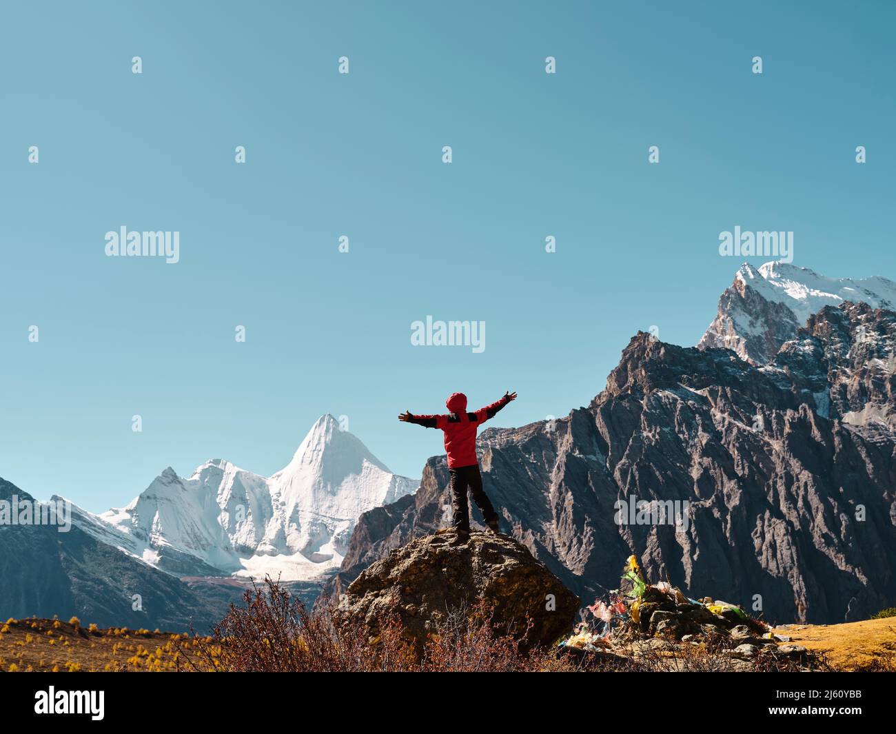 Vue arrière de l'homme asiatique debout au-dessus du rocher regardant le sommet de Yangmaiyong (ou Jampayang en tibétain) avec des bras ouverts à Yading, Daocheng Count Banque D'Images