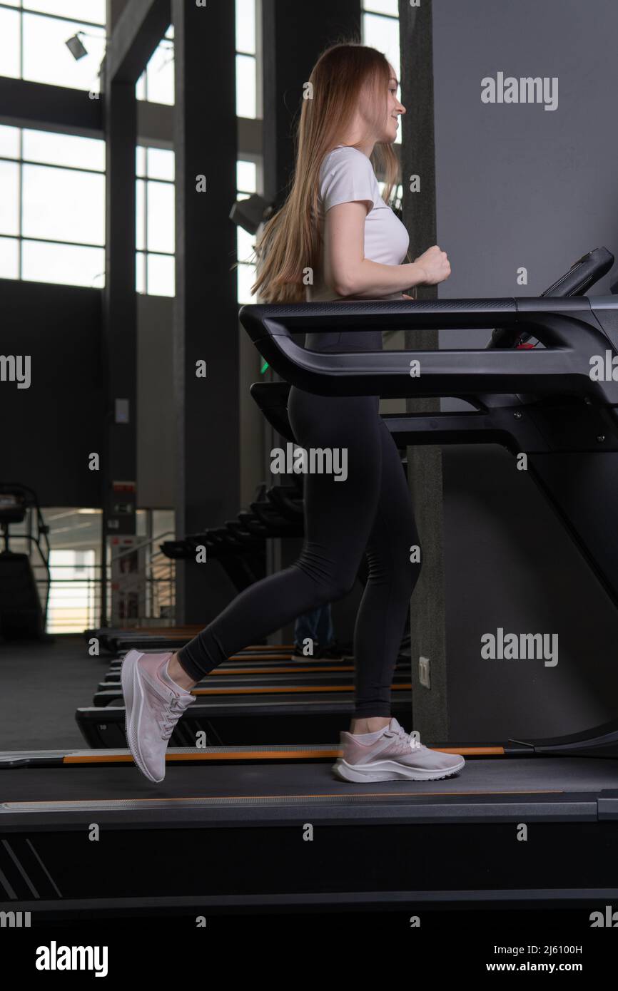 Jeune femme longueur à l'intérieur profil de tapis roulant plein exercice personnes, pour la forme d'entraînement pour caucasien pour l'entraînement récréation, coureur athlétique. Jambes blanches Banque D'Images