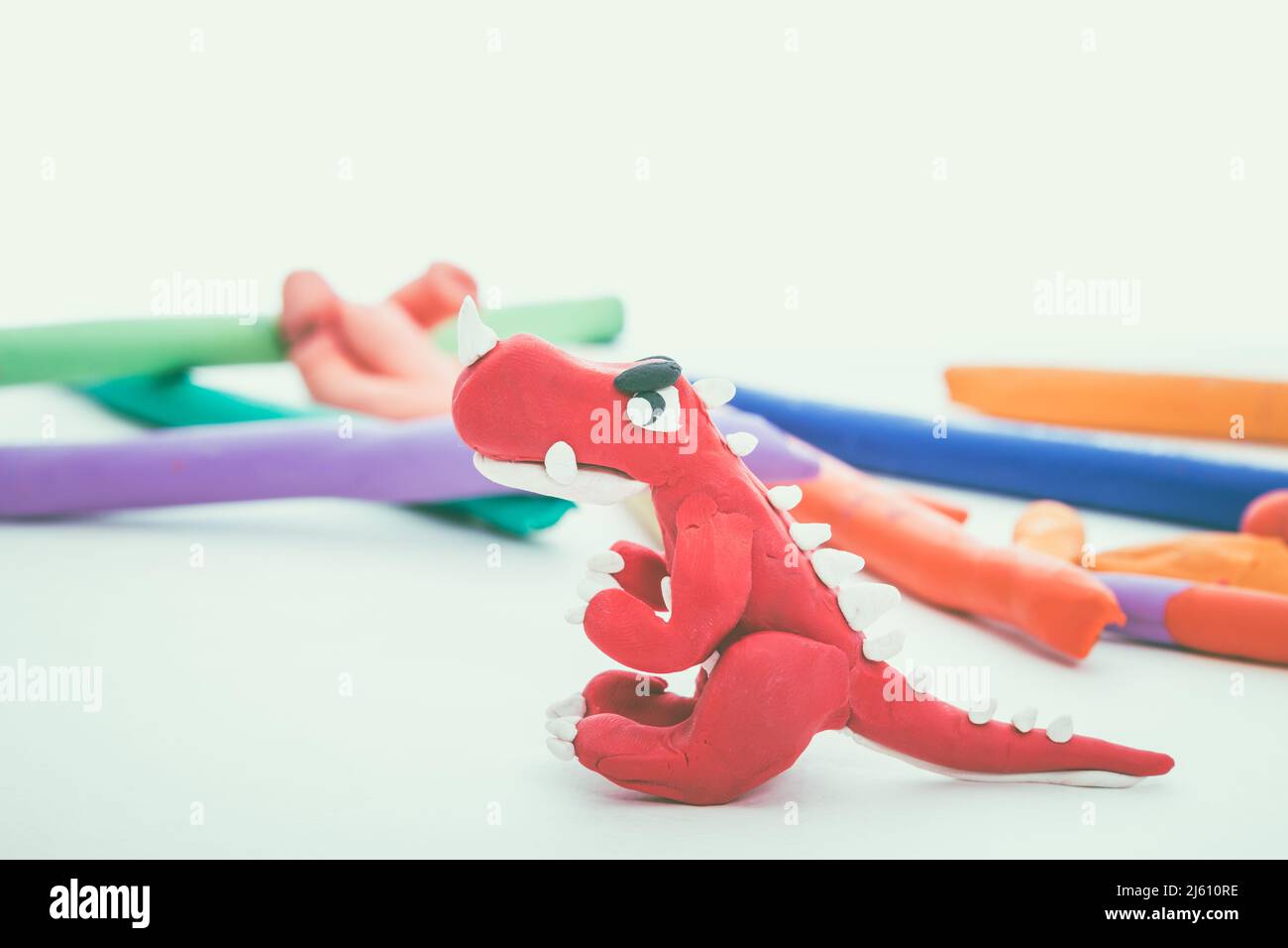 Bel animal de pâte de jeu. Modèle animal en argile créatif. Dinosaure rouge des enfants Bright play Dough. Prise de vue en studio. Effet de ton vintage. Banque D'Images