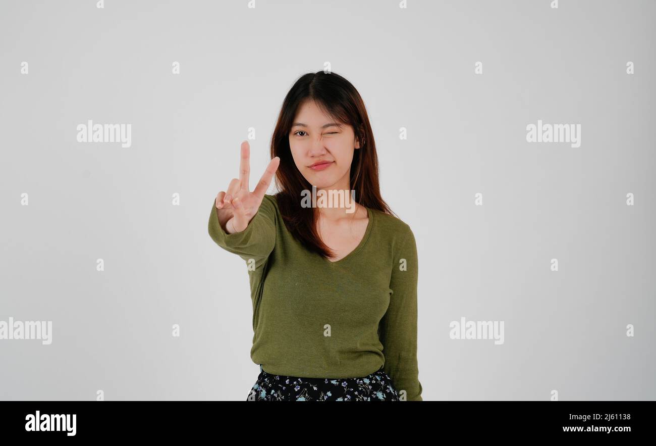 Jeune femme asiatique montrant deux doigts, un geste positif ou un geste de paix, sur fond blanc Banque D'Images