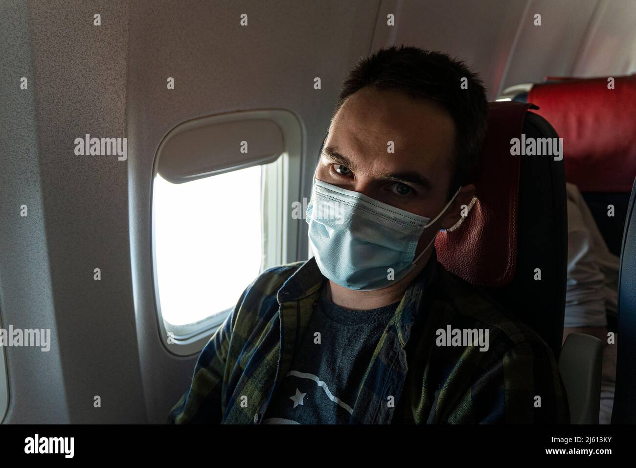 Un homme portant un masque facial assis dans un avion. Nouveau voyage normal pendant une pandémie. Homme passager voyageant. Porter un masque dans la cabine de l'avion Banque D'Images