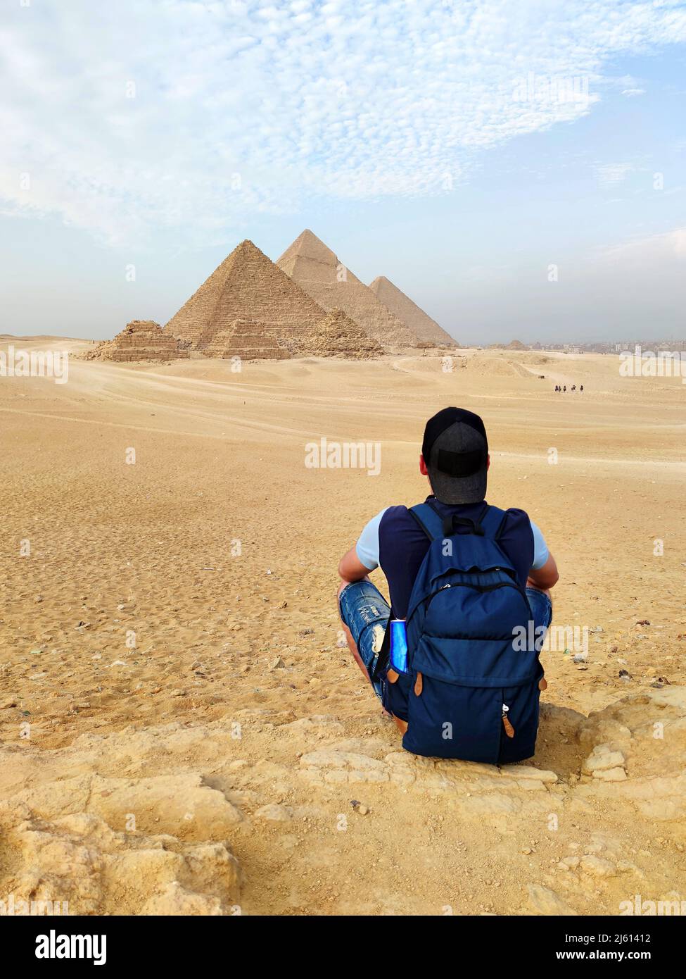 Égypte. Le Caire - Gizeh. Jeune blonde touriste fille avec un sac à dos est assis sur le sable regardant la vue générale des pyramides du plateau de Gizeh. Profitez Banque D'Images