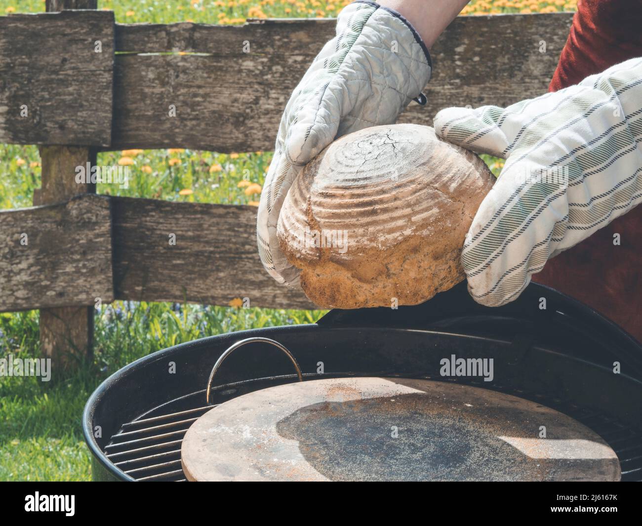 utilisez des gants de cuisine pour retirer le pain fait maison du barbecue ou du gril à charbon de bois après avoir fait cuire le meilleur pain jamais Banque D'Images