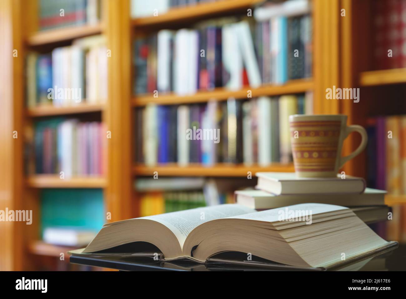 bibliothèque avec de nombreux livres à lire, disposés sur des étagères. Ouvrez le livre et le gobelet en gros plan. Copier l'espace. Arrière-plan. Banque D'Images