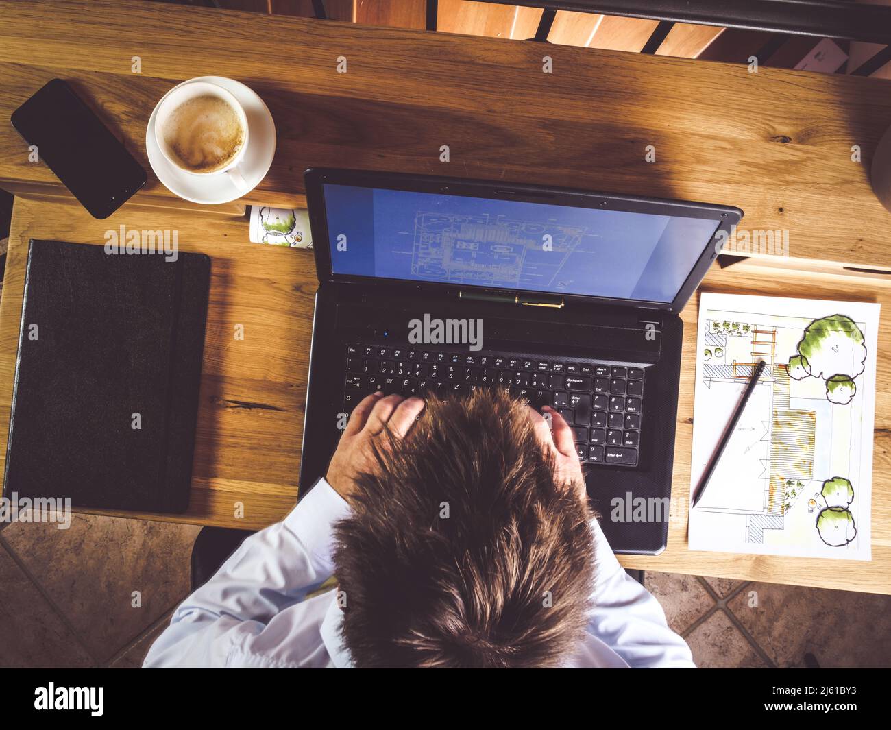 l'image montre une vue de dessus de l'homme d'affaires travaillant à la maison avec ordinateur portable et bloc-notes, bureau en bois et plan de jardin ou design à l'arrière-plan Banque D'Images