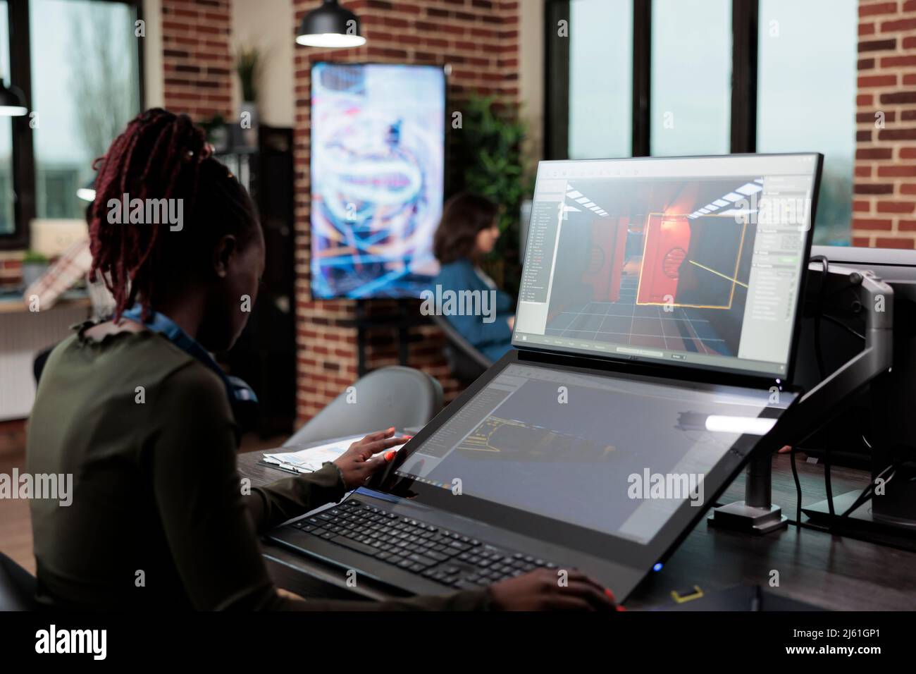 Artiste numérique assis au bureau, utilisant un PC pour concevoir l'environnement et les niveaux de jeu. Le créateur du département de développement travaille avec CGI pour atteindre le réalisme virtuel. Banque D'Images