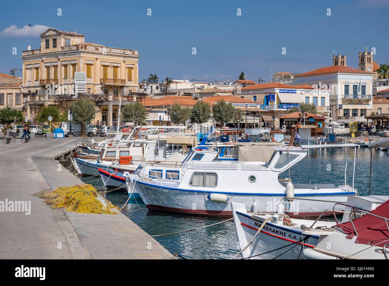 Île d'Aegina Grèce - 4.27.2022: Vue sur le front de mer avec des bateaux de pêche dans le port et des bâtiments et maisons typiques grecs en arrière-plan Banque D'Images