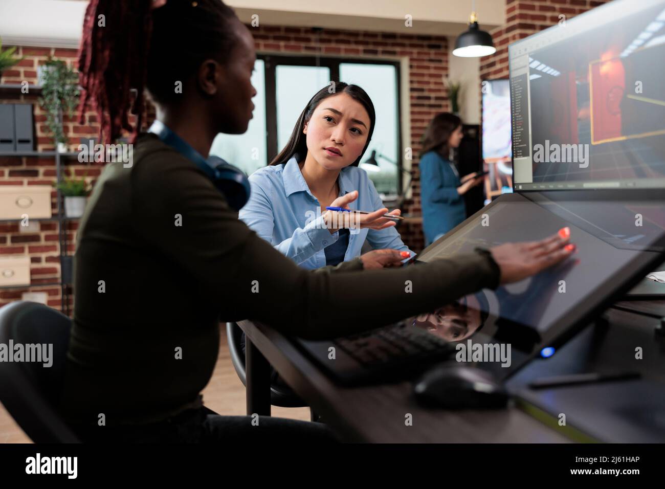 Développement de jeux agences créatives artistes conversant sur la conception de niveau et 3D actifs tout en étant assis dans un espace de travail de bureau. Travailleurs de l'industrie du divertissement interactif numérique travaillant avec CGI. Banque D'Images