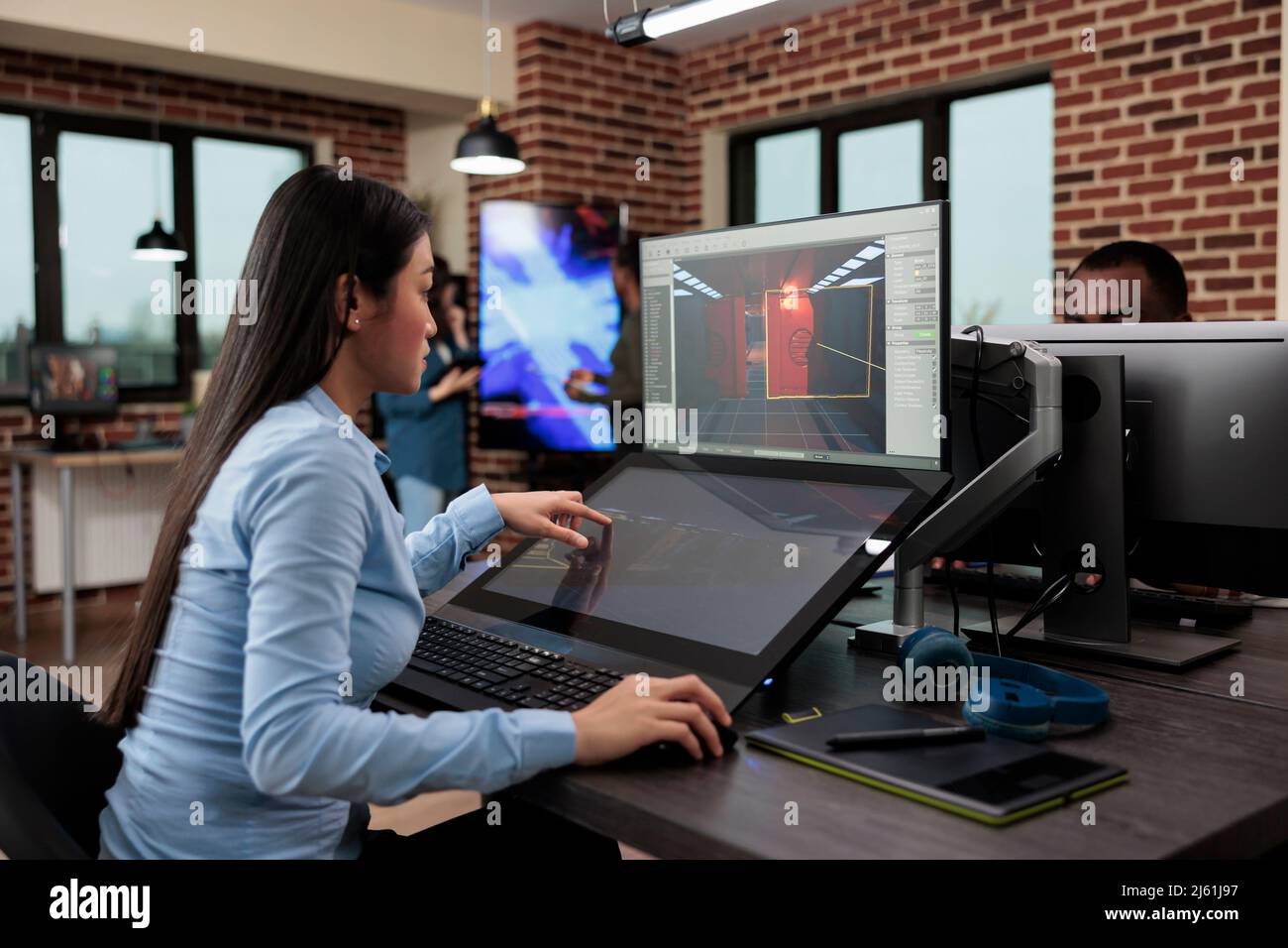 Développeur de jeux d'entreprise créative, assis dans le département de production tout en développant 3D scènes et environnement de jeux vidéo. Employé asiatique travaillant sur la conception de niveau à l'aide de logiciels modernes. Banque D'Images
