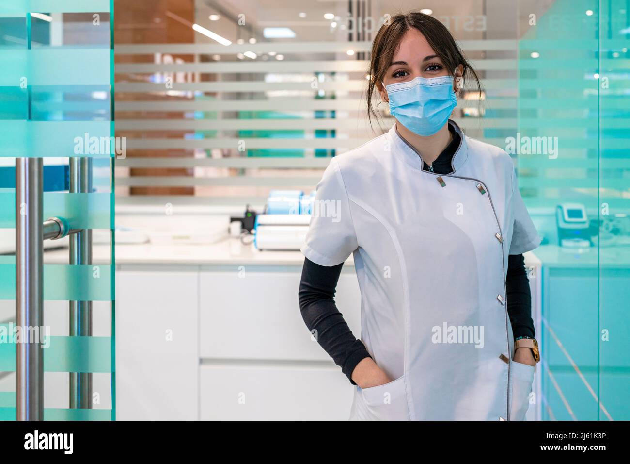 Infirmière dans le masque facial de protection debout avec les mains dans les poches à l'hôpital Banque D'Images