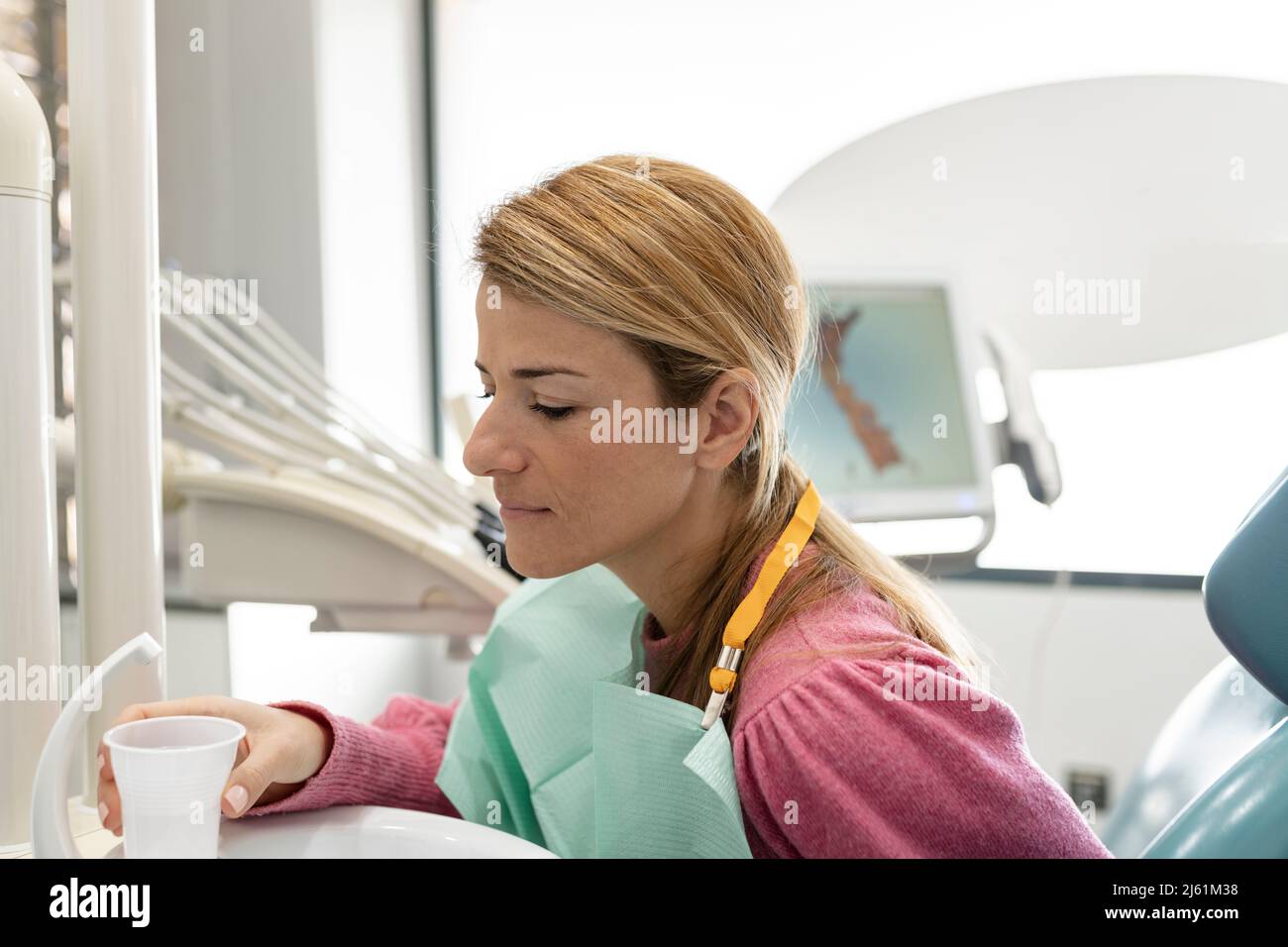 Patient avec un verre d'eau assis à la clinique dentaire Banque D'Images