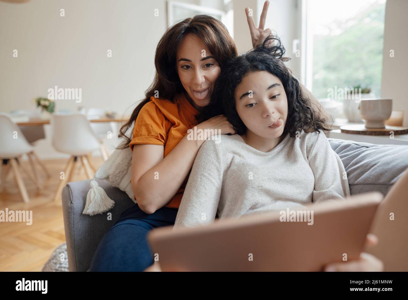 Une femme et une fille qui s'encollent sur des langues et qui prennent le selfie à la maison à travers un Tablet PC Banque D'Images