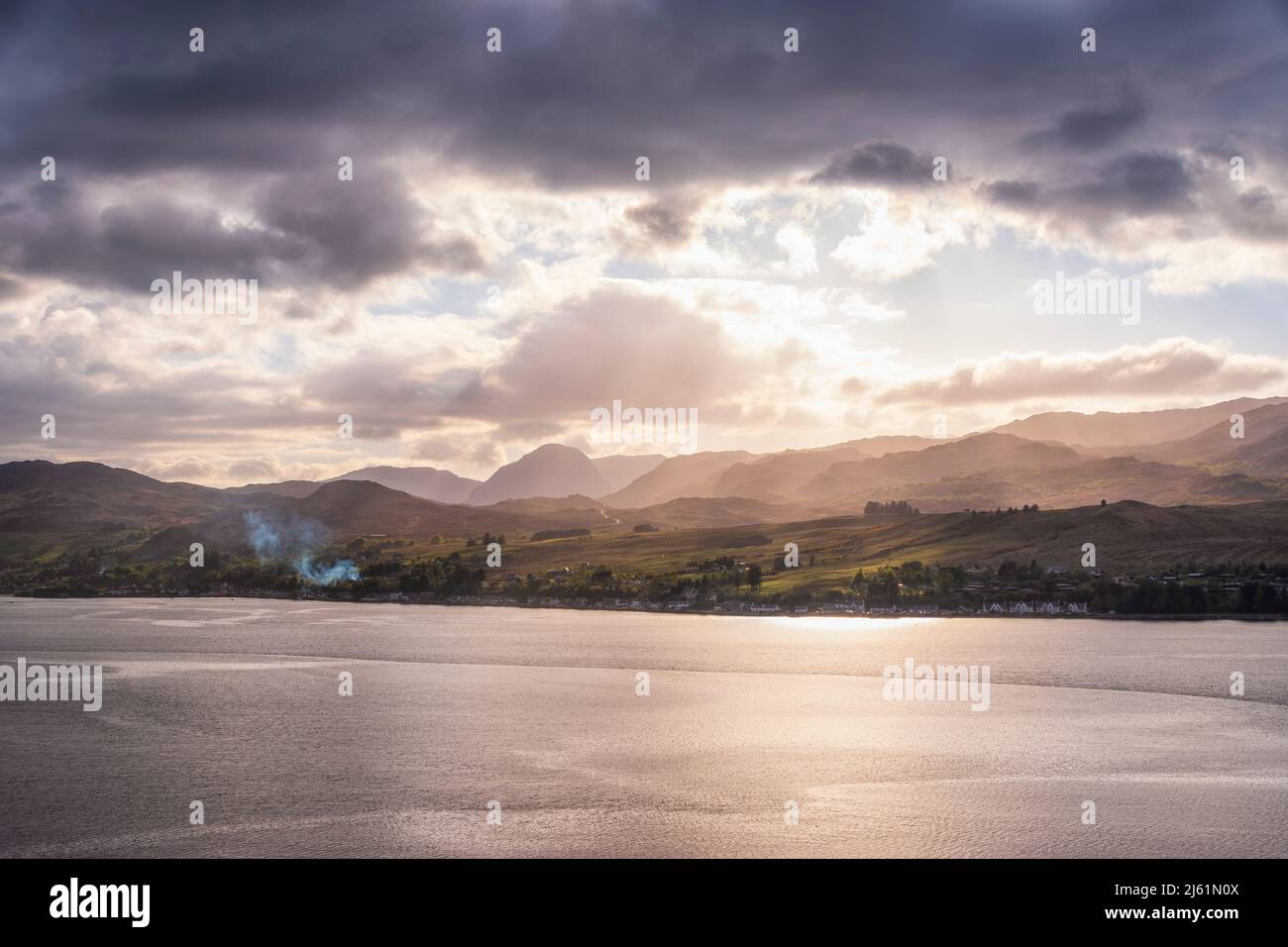 Vue panoramique sur la mer avec montagnes en arrière-plan sous ciel nuageux au coucher du soleil Banque D'Images