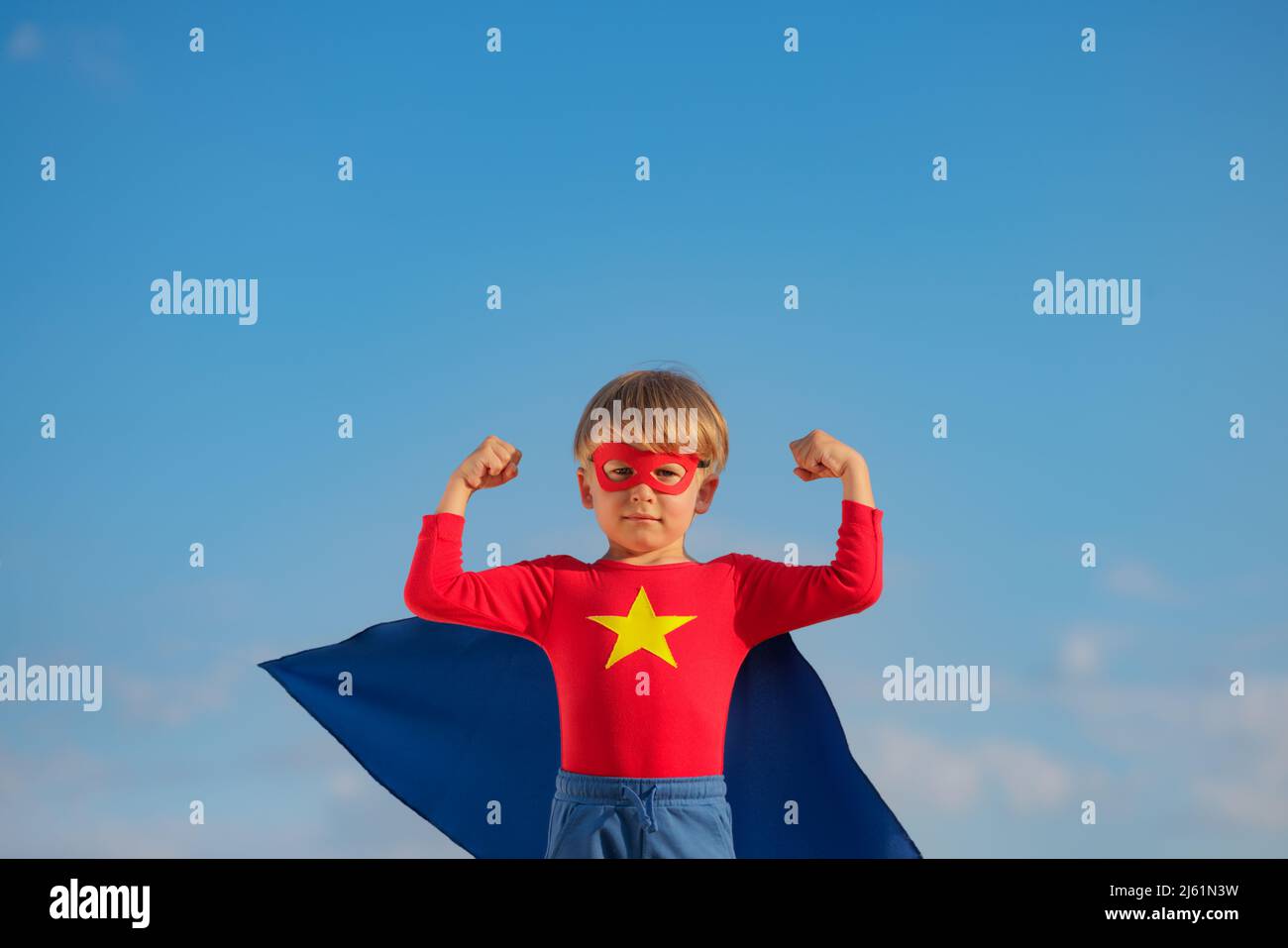 Enfant super-héros jouant à l'extérieur. Super héros Kid contre fond bleu ciel d'été. Imagination et liberté Banque D'Images