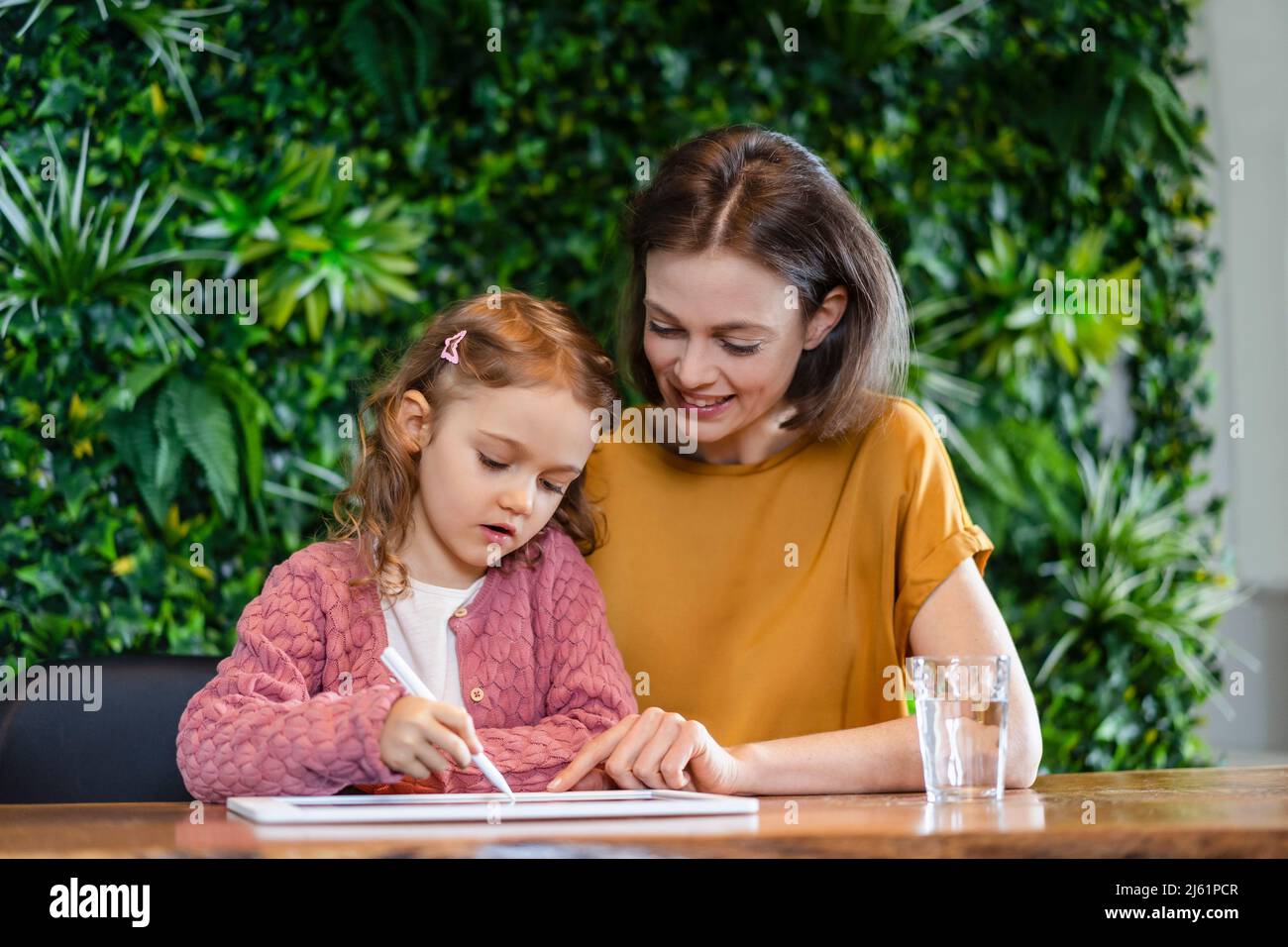 Une mère souriante aide sa fille à utiliser un Tablet PC à la maison Banque D'Images