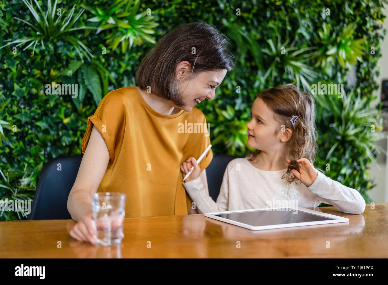 Bonne mère avec un verre d'eau aidant la fille à la maison Banque D'Images