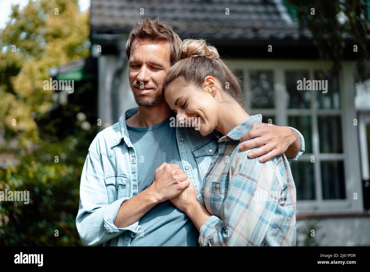 Homme souriant debout avec le bras autour de la femme à l'arrière-cour Banque D'Images