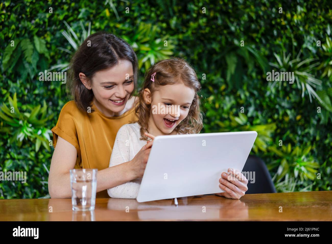 Bonne mère aidant sa fille sur un PC tablette à la maison Banque D'Images