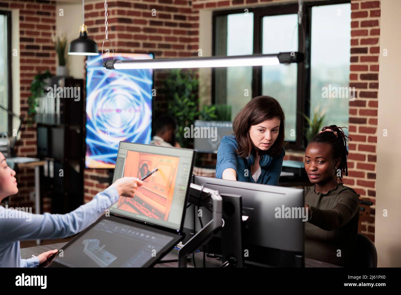 3D graphistes dans l'espace de travail de bureau d'agence de création développant un projet de jeu vidéo. Entreprise divers employés discutent des progrès du développement et des arts électroniques Banque D'Images
