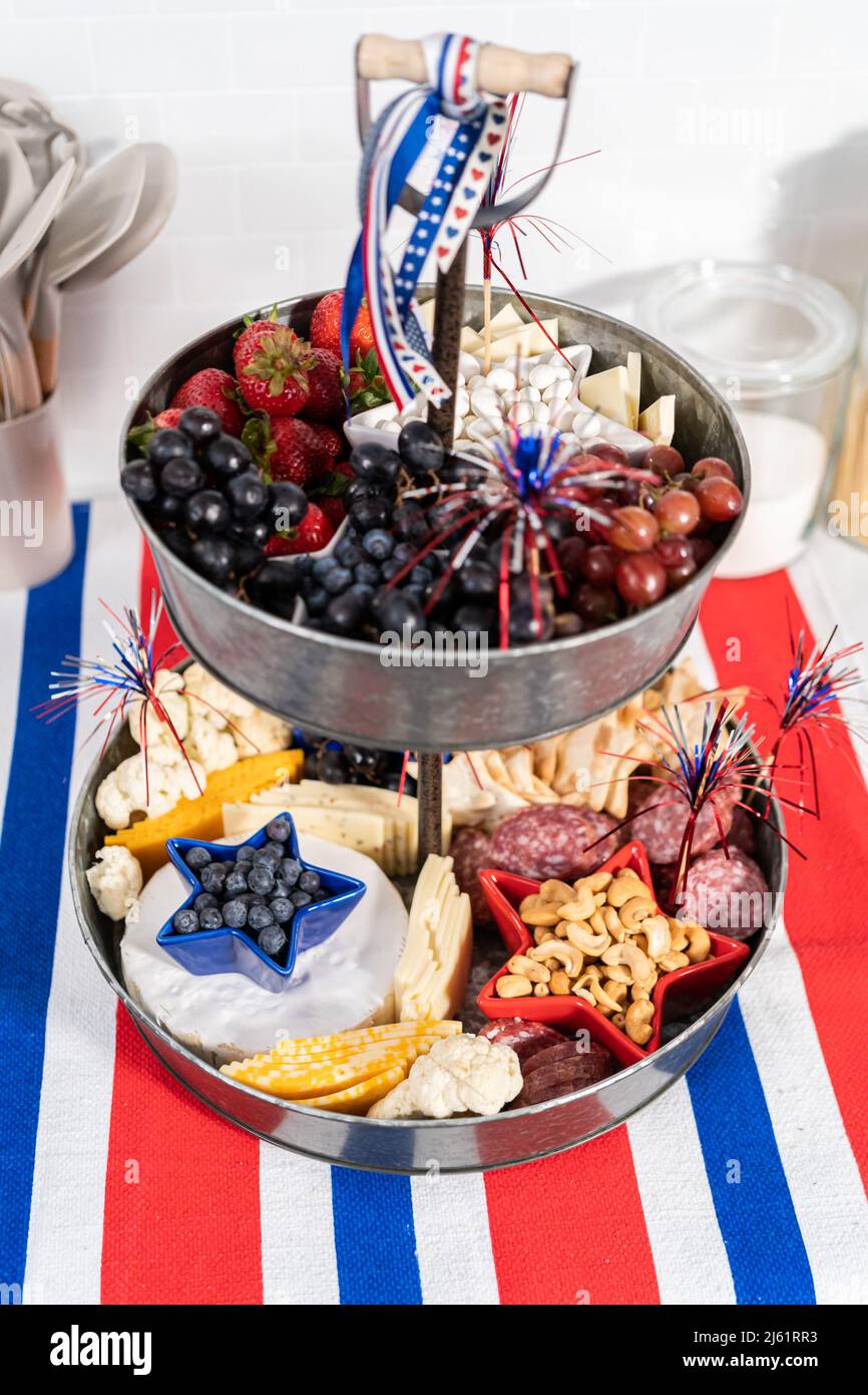 Le 4 juillet, un plateau de charcuterie est servi sur un support métallique à deux niveaux rempli de fromage, de craquelins, de salami et de fruits frais Banque D'Images