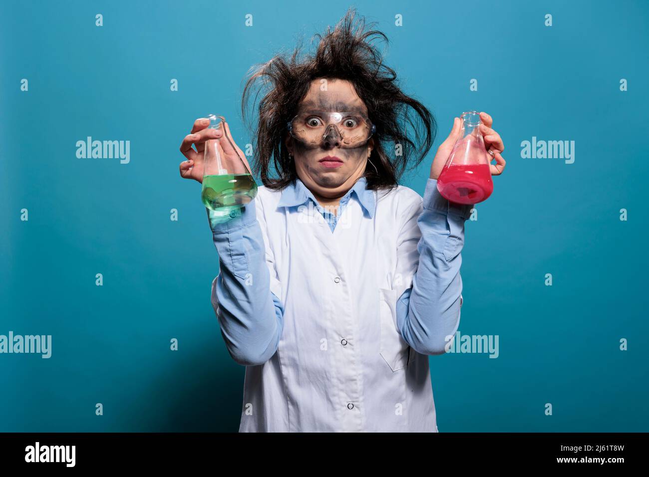 Chimiste fou avec visage sale et cheveux dsordonns ayant des flacons  remplis de substances chimiques inconnues. Un spcialiste de la chimie qui  tient des bchers en verre remplis de composs liquides dangereux