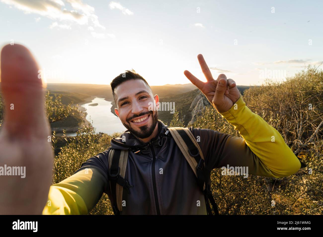 Un randonneur masculin fait un geste de paix tout en prenant le selfie dans le parc national de Monfrague Banque D'Images