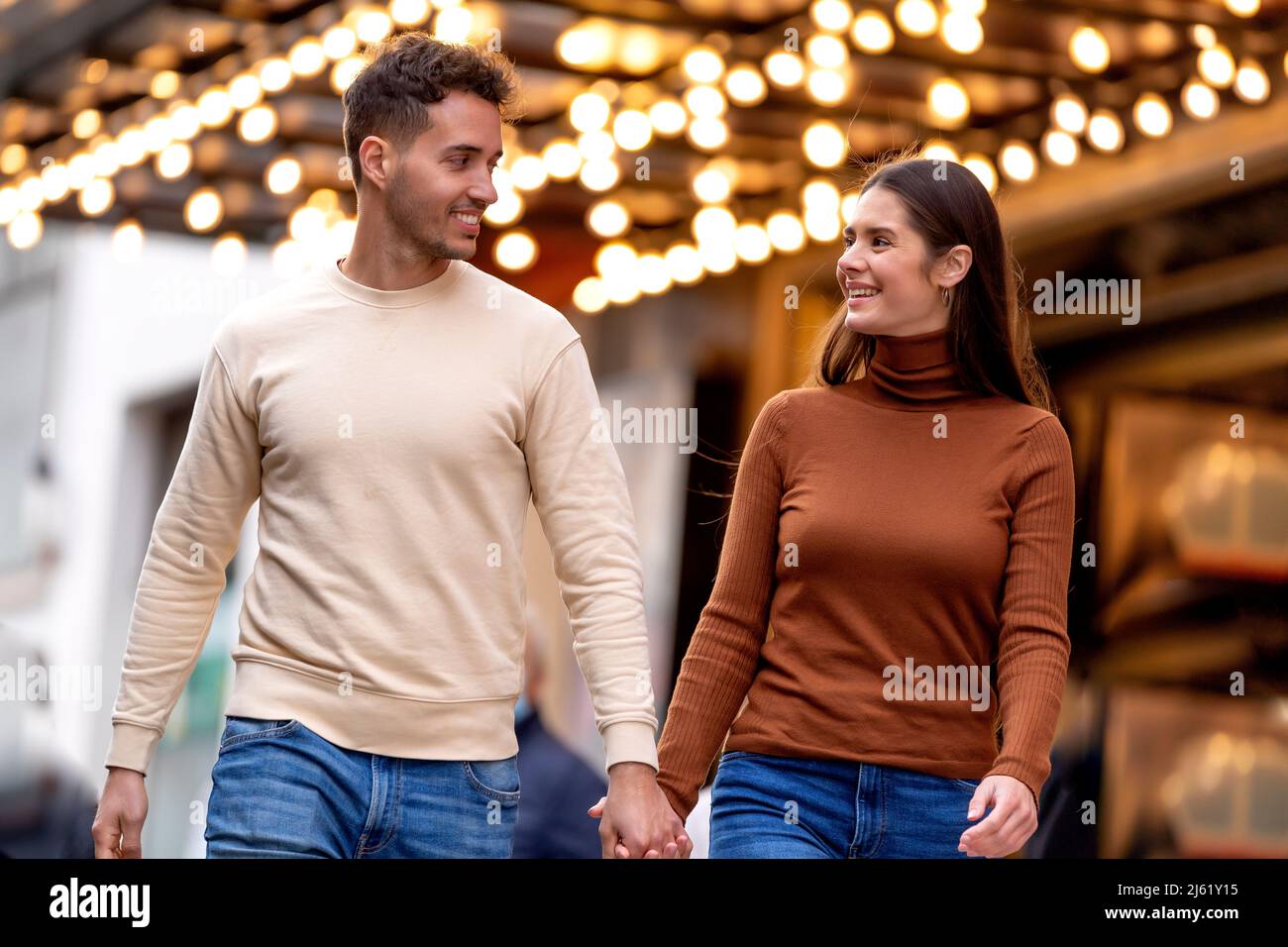 Couple souriant marchant avec les mains en face du plafond éclairé Banque D'Images