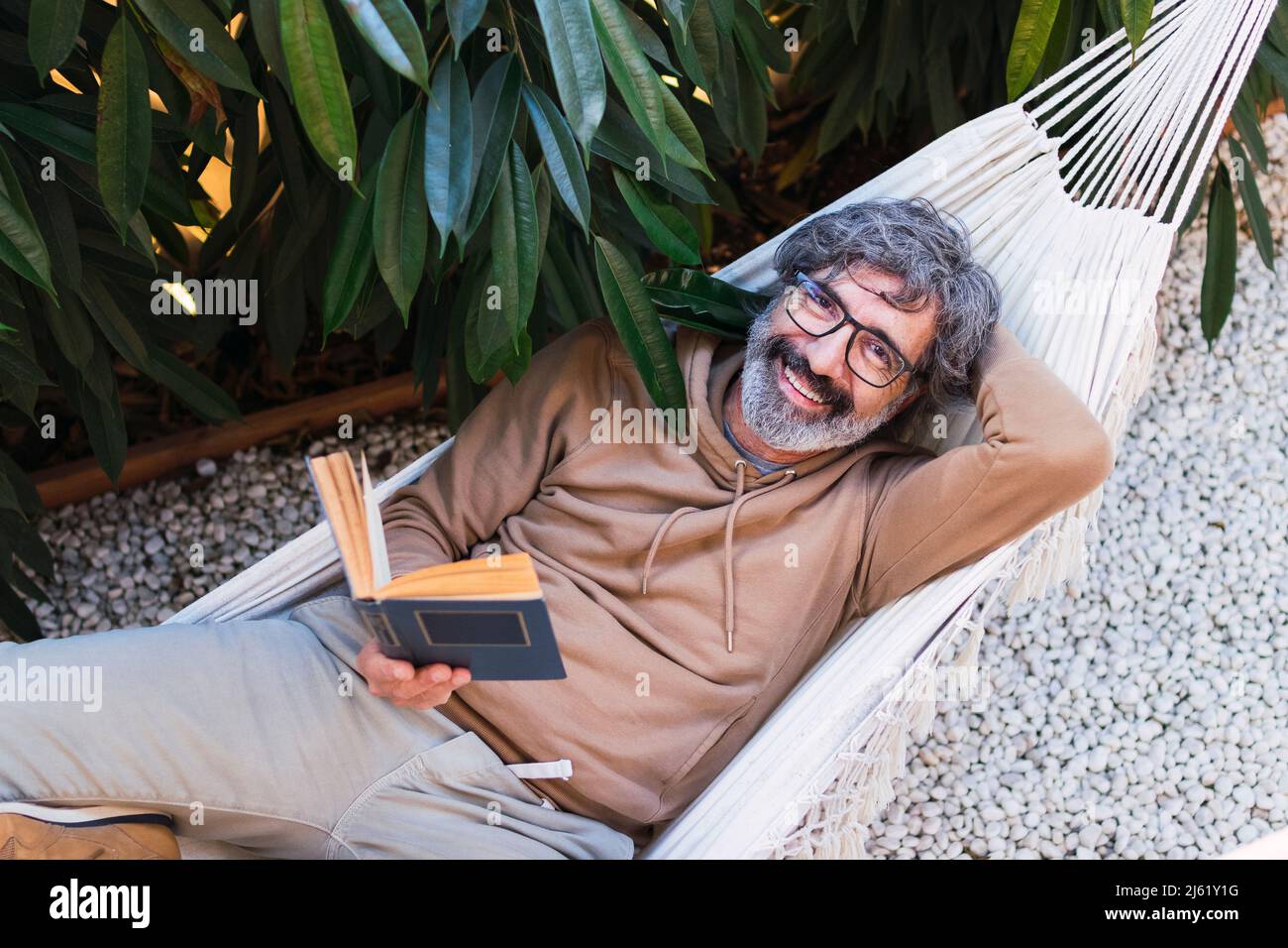Homme de lecture de livre par hamac dans l'arrière-cour Photo Stock - Alamy