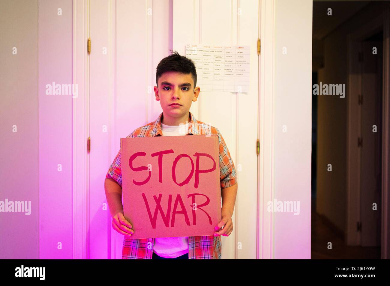 Garçon avec étiquette STOP WAR debout devant la porte à la maison Banque D'Images