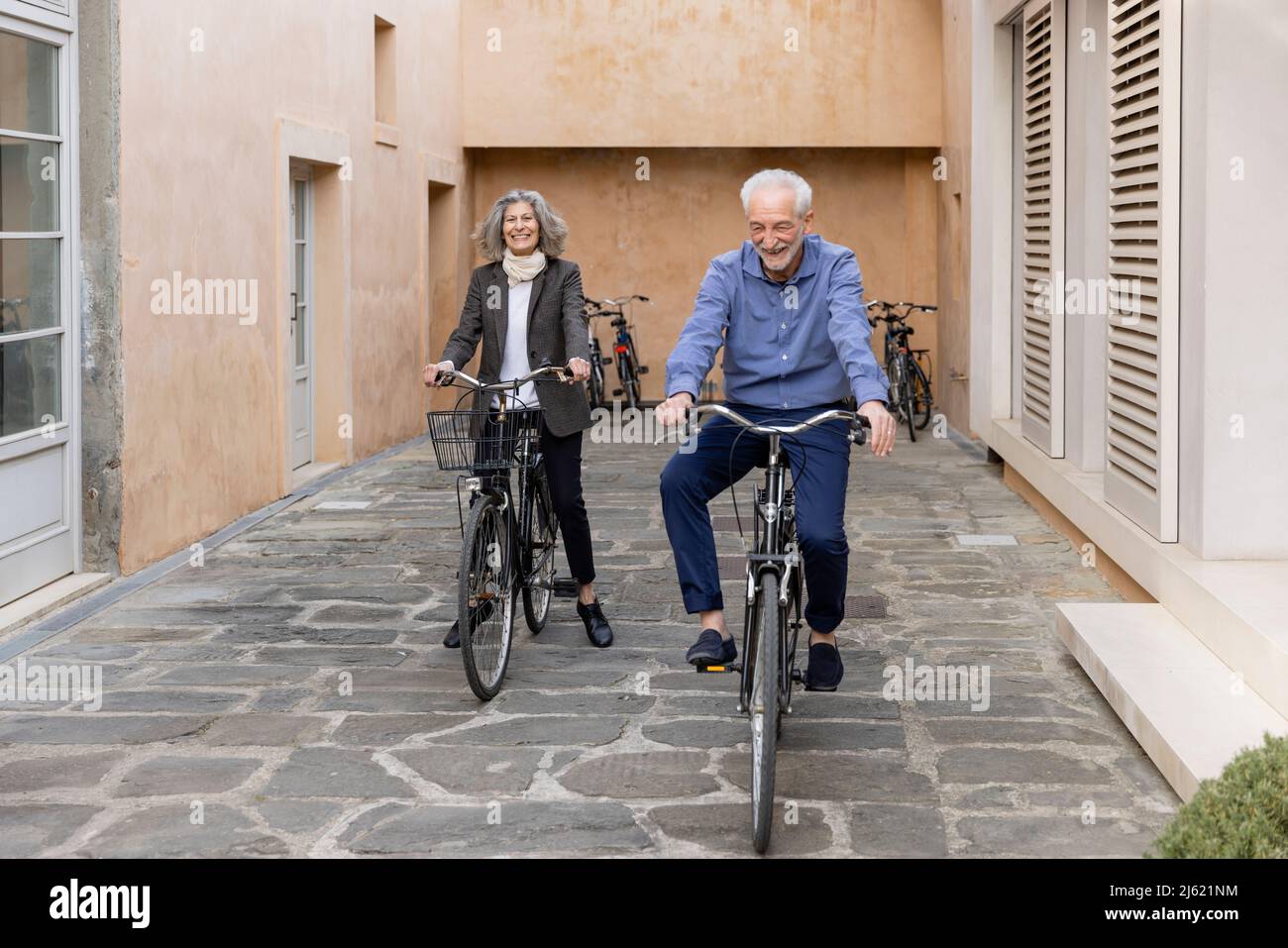 Couple senior souriant à vélo sur une piste de randonnée Banque D'Images