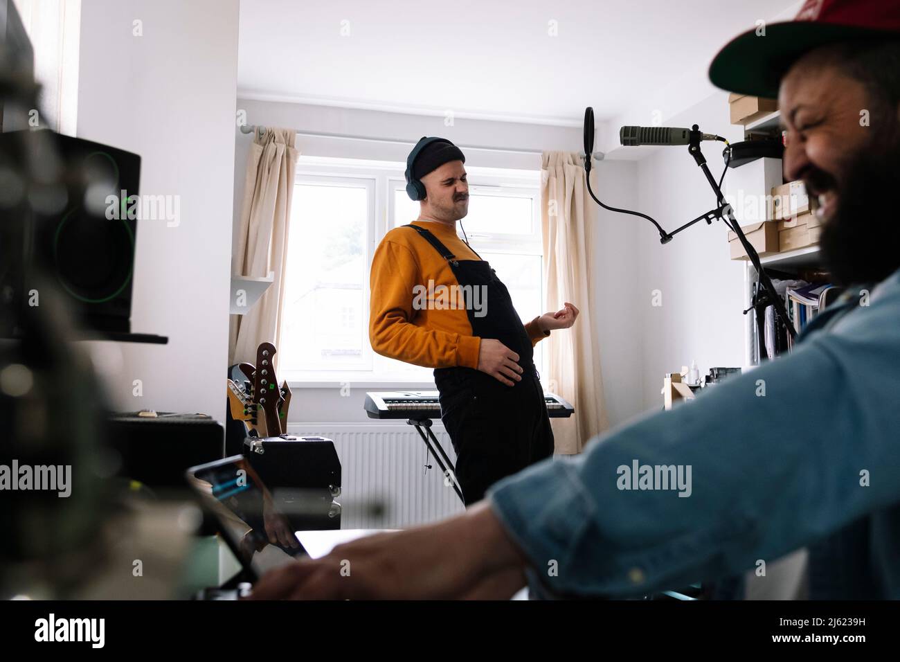 Chanteur et ingénieur du son pratiquant la musique dans un studio à domicile Banque D'Images