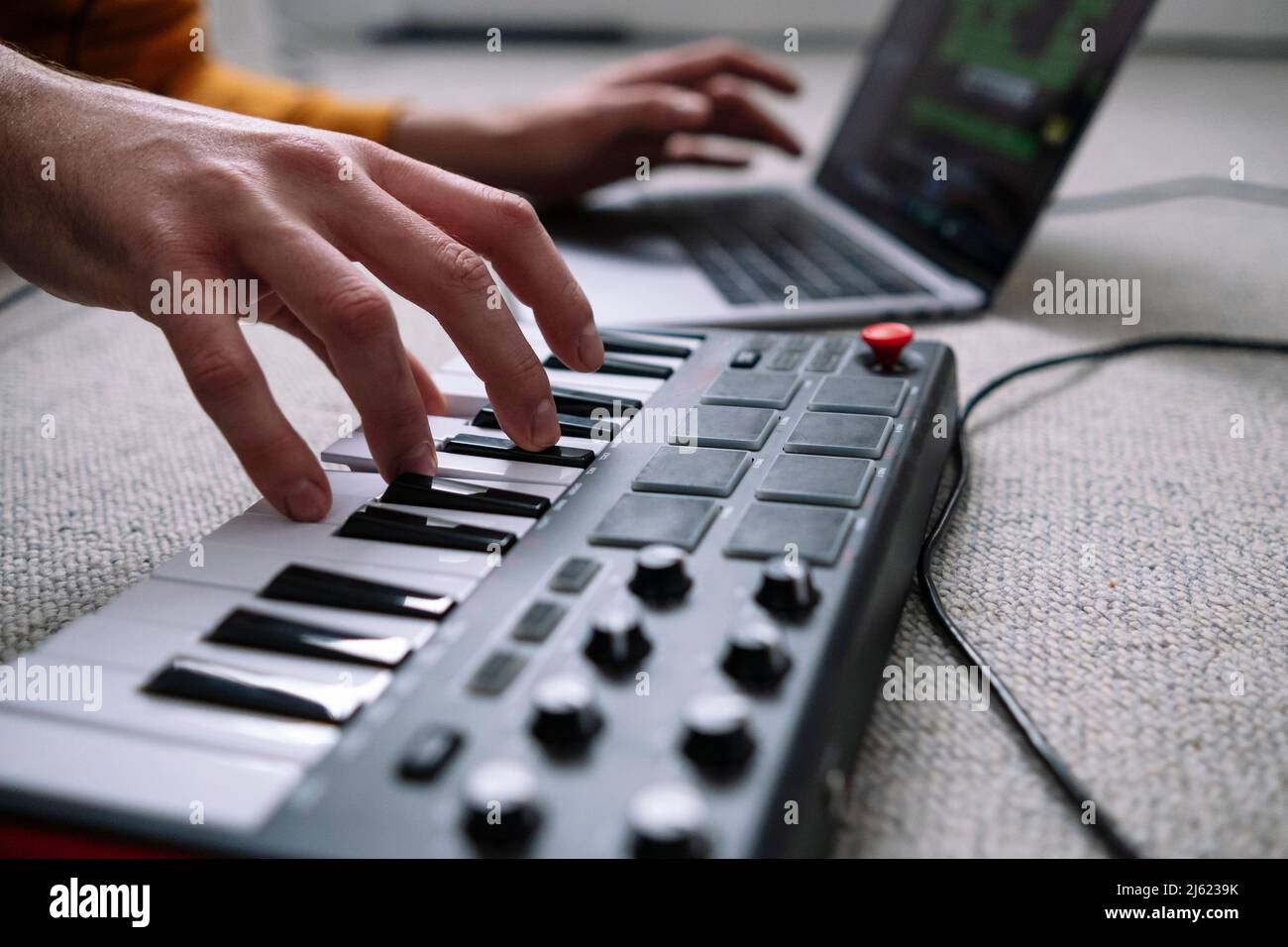 Mains de freelance utilisant un ordinateur portable et piano dans studio à la maison Banque D'Images