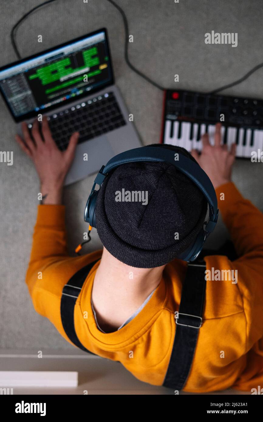 Indépendant créant de la musique avec un ordinateur portable et un piano dans un studio à domicile Banque D'Images