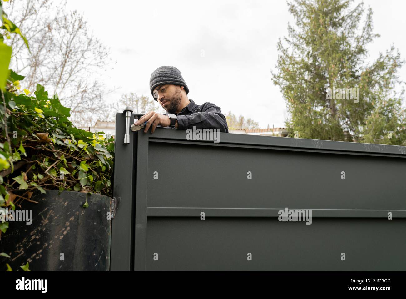 Ouvrier de la construction installant des verrous sur la barrière métallique Banque D'Images