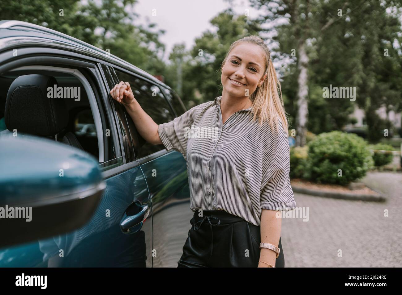 Femme souriante debout en voiture sur le parking Banque D'Images