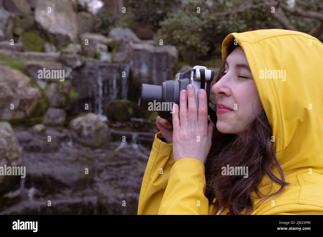 Jeune femme regardant à travers l'appareil photo photographier dans la forêt Banque D'Images