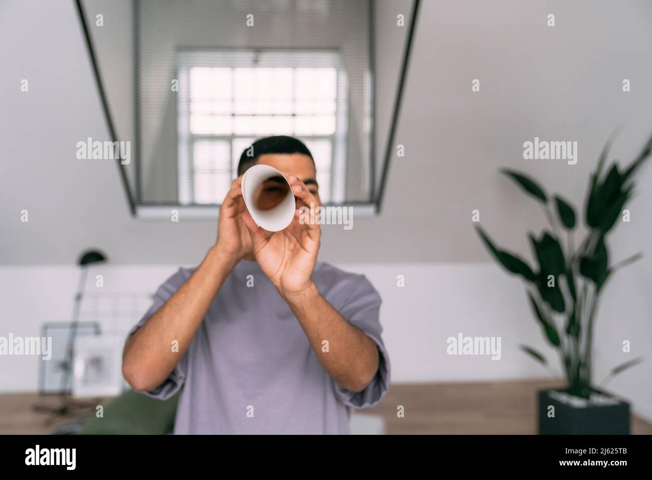 Jeune homme regardant à travers le papier plié à la maison Banque D'Images
