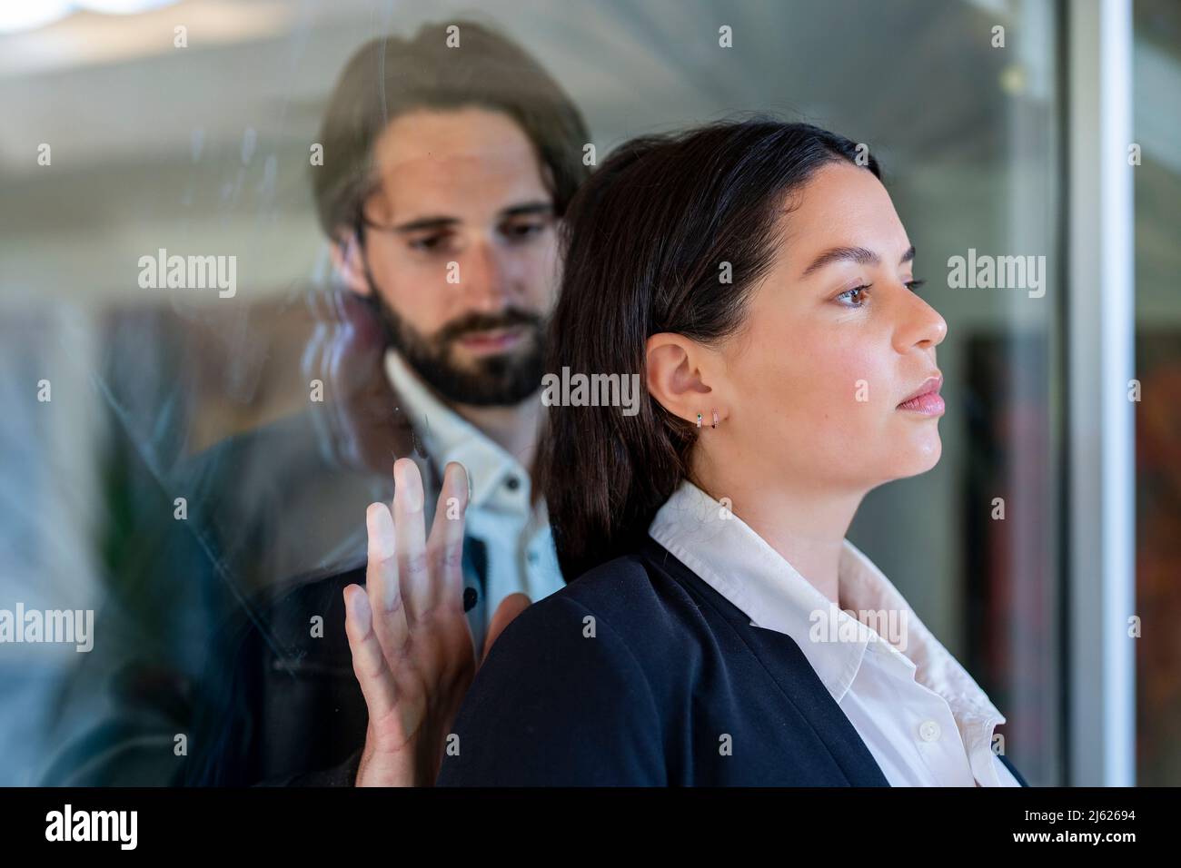 Triste homme touchant l'arrière de la femme séparé par le panneau de verre Banque D'Images
