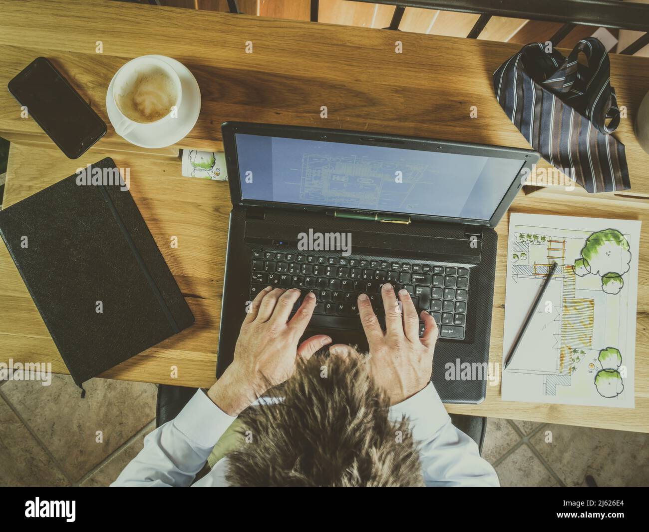 l'image montre une vue de dessus de l'homme d'affaires travaillant à la maison travaillant sur ordinateur portable au bureau à la maison écrivant sur ordinateur portable ou ordinateur, bureau en bois, café et plan de jardin Banque D'Images