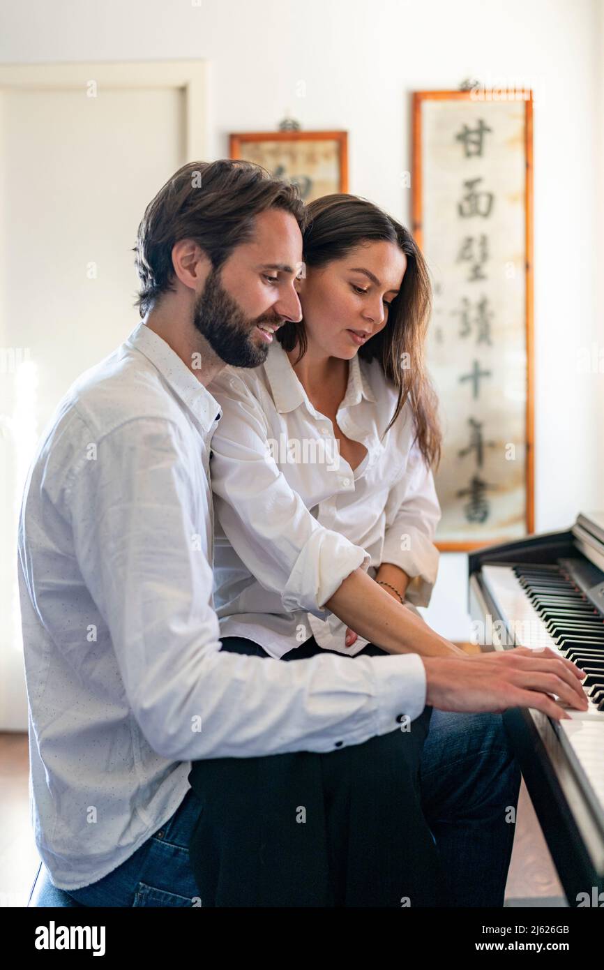 Couple jouant du piano assis les uns à côté des autres Photo Stock - Alamy