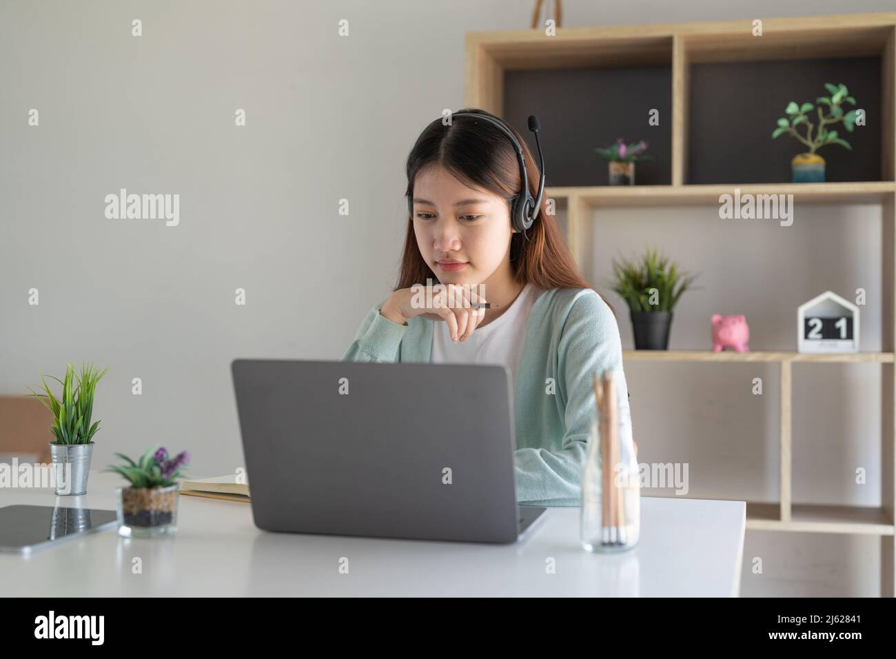 Concentrez-vous asiatique gial freelance portant un casque, communiquant avec le client via un appel vidéo sur ordinateur. Tuteur féminin professionnel agréable millénaire Banque D'Images