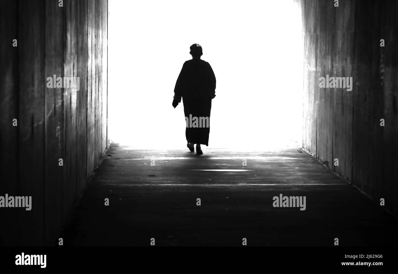 Une silhouette de figure noire et blanche à contraste élevé dans un paysage d'une seule dame ou d'une seule femme qui marche ou à travers un tunnel dans et double une Banque D'Images