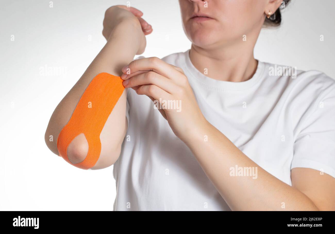La fille colle une bande kinésiologique orange sur sa main. Muscles et ligaments de bande Banque D'Images