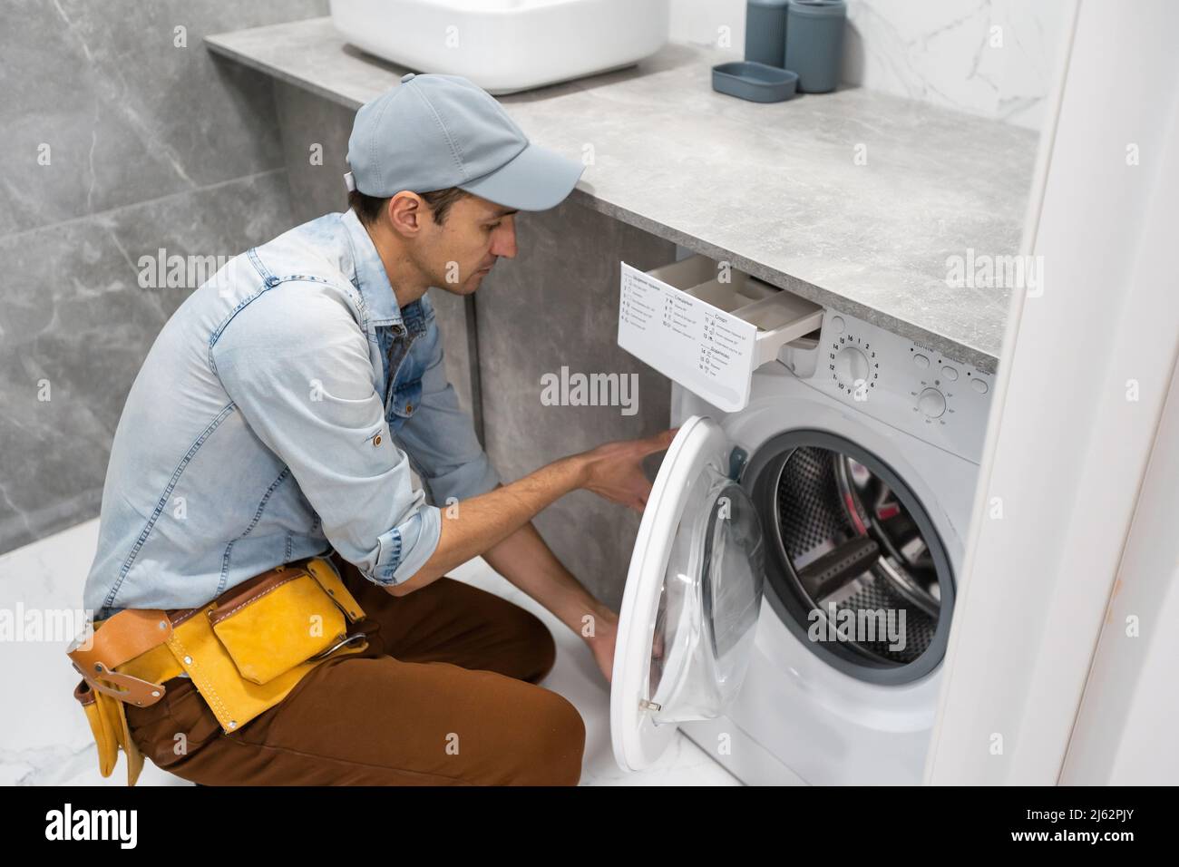 L'homme travail plombier réparation d'un lave-linge dans la blanchisserie  Photo Stock - Alamy
