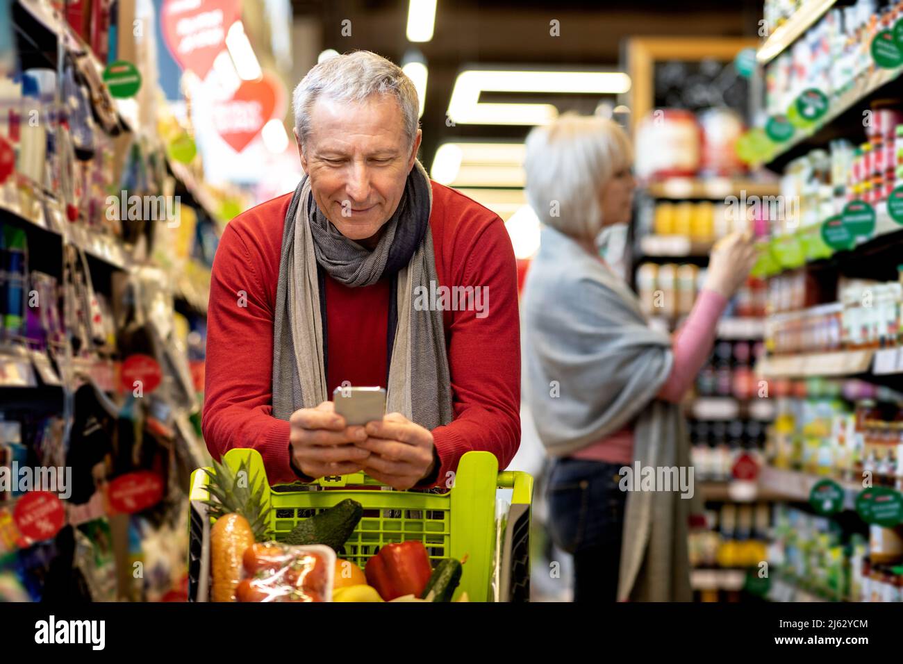 Homme senior vérifiant la liste d'achats sur smartphone, achetant avec sa femme Banque D'Images