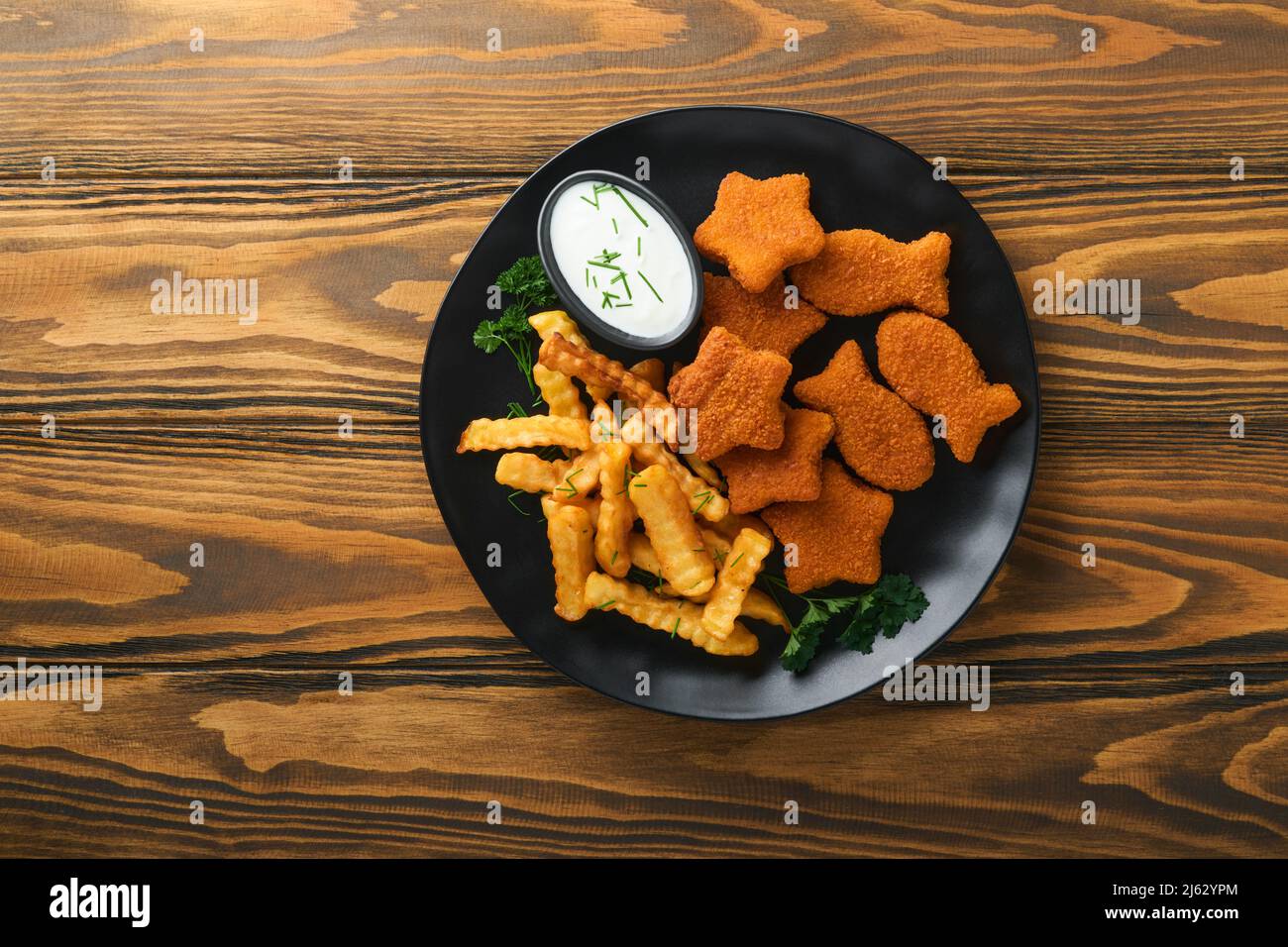 Fish and Chips, restauration rapide britannique. Bâtonnets de poisson avec frites sur plaque noire sur fond de table en bois. Plat traditionnel britannique authentique Banque D'Images
