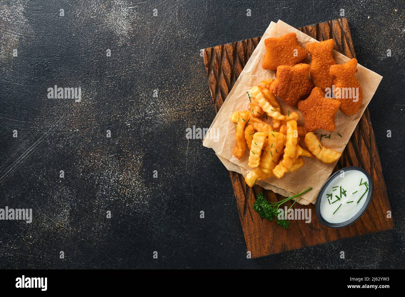 Fish and Chips, restauration rapide britannique. Bâtonnets de poisson avec frites sur un panneau rustique sur fond de vieux béton foncé. Traditionnelle britannique authentique str Banque D'Images