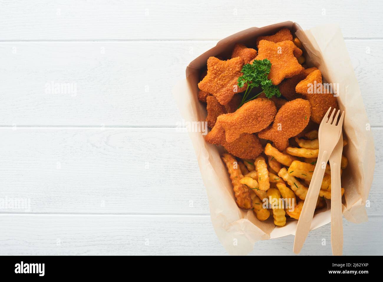 Fish and Chips, restauration rapide britannique. Bâtonnets de poisson avec frites sur une assiette en papier à emporter sur fond en bois blanc. Authentique britannique traditionnel Banque D'Images