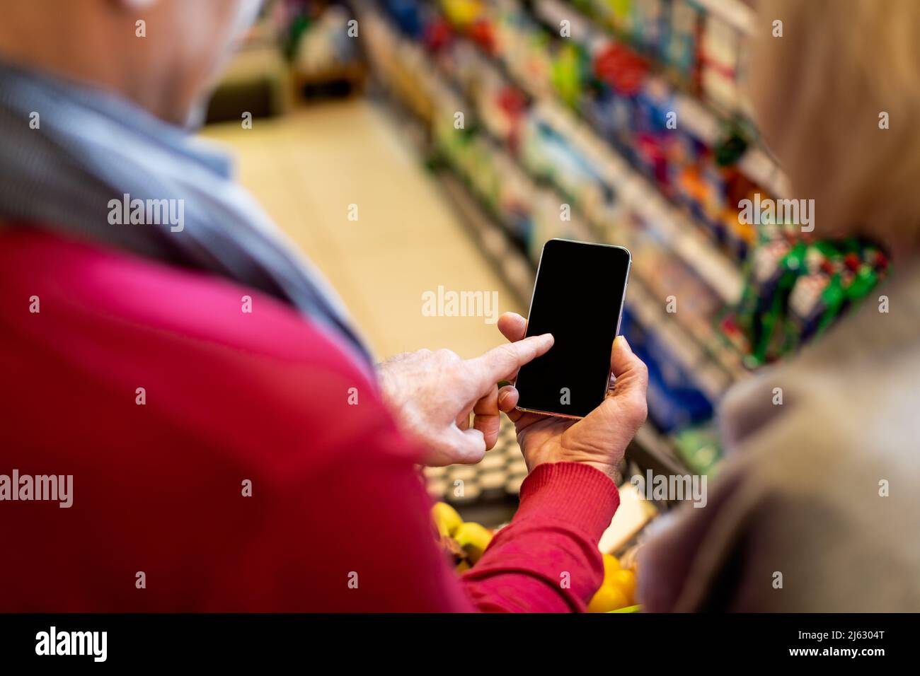 Clients méconnaissables achetant de la nourriture en magasin, utilisant un smartphone, mockup Banque D'Images