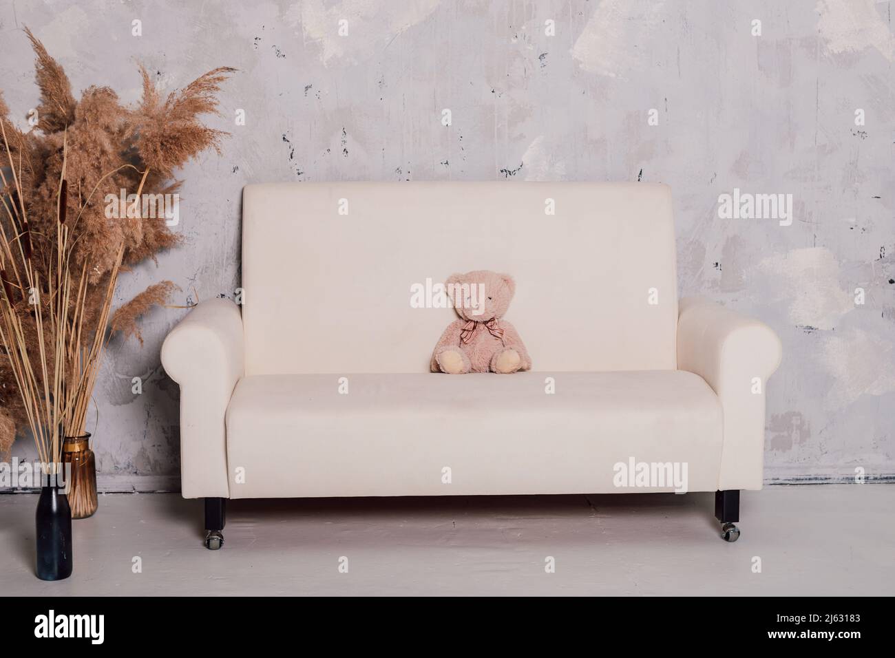 L'ours en peluche se trouve sur un magnifique canapé blanc Banque D'Images